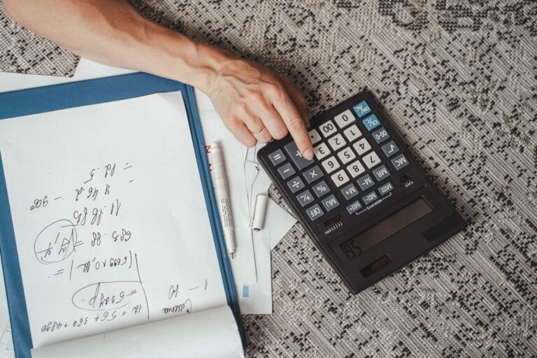 Mãos realizam cálculos com calculadora e anotações