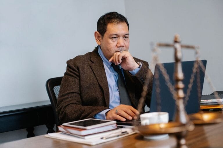Profissional consulta computador ao lado de balança da Justiça