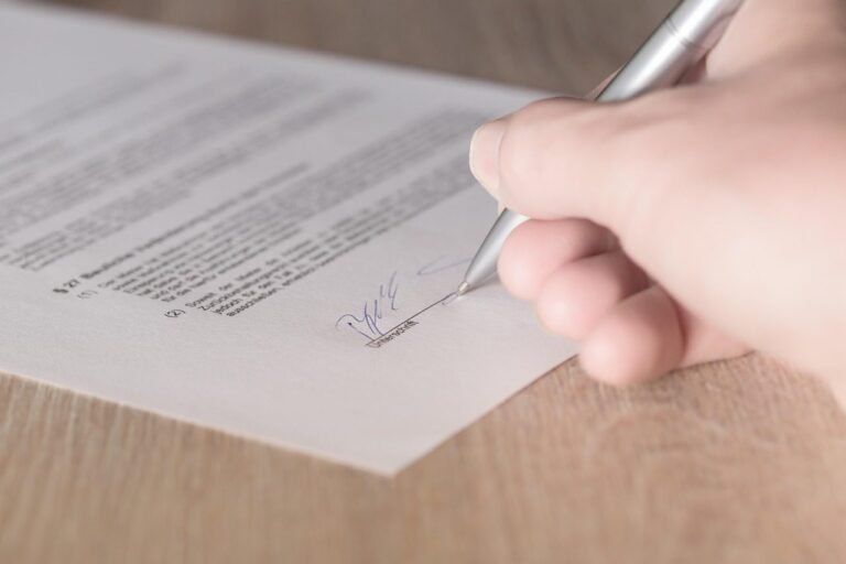 Mão assinando um contrato impresso com caneta prateada