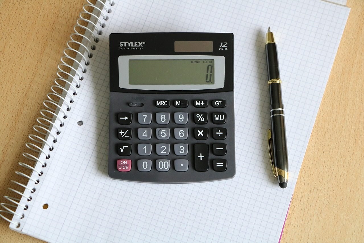Calculadora e caneta sobre um bloco quadriculado