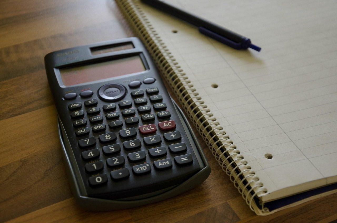 Calculadora e caneta sobre um bloco espiral pautado