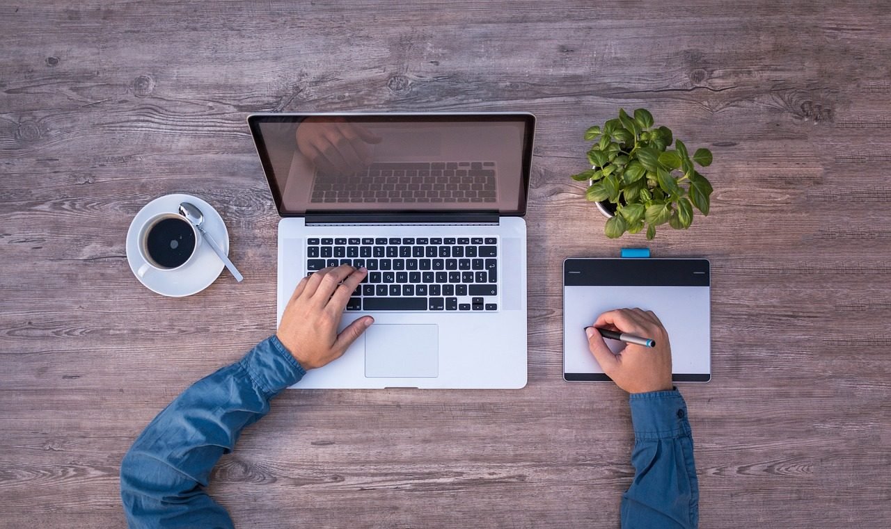Duas pessoas trabalhando em notebook e tablet, vistas de cima