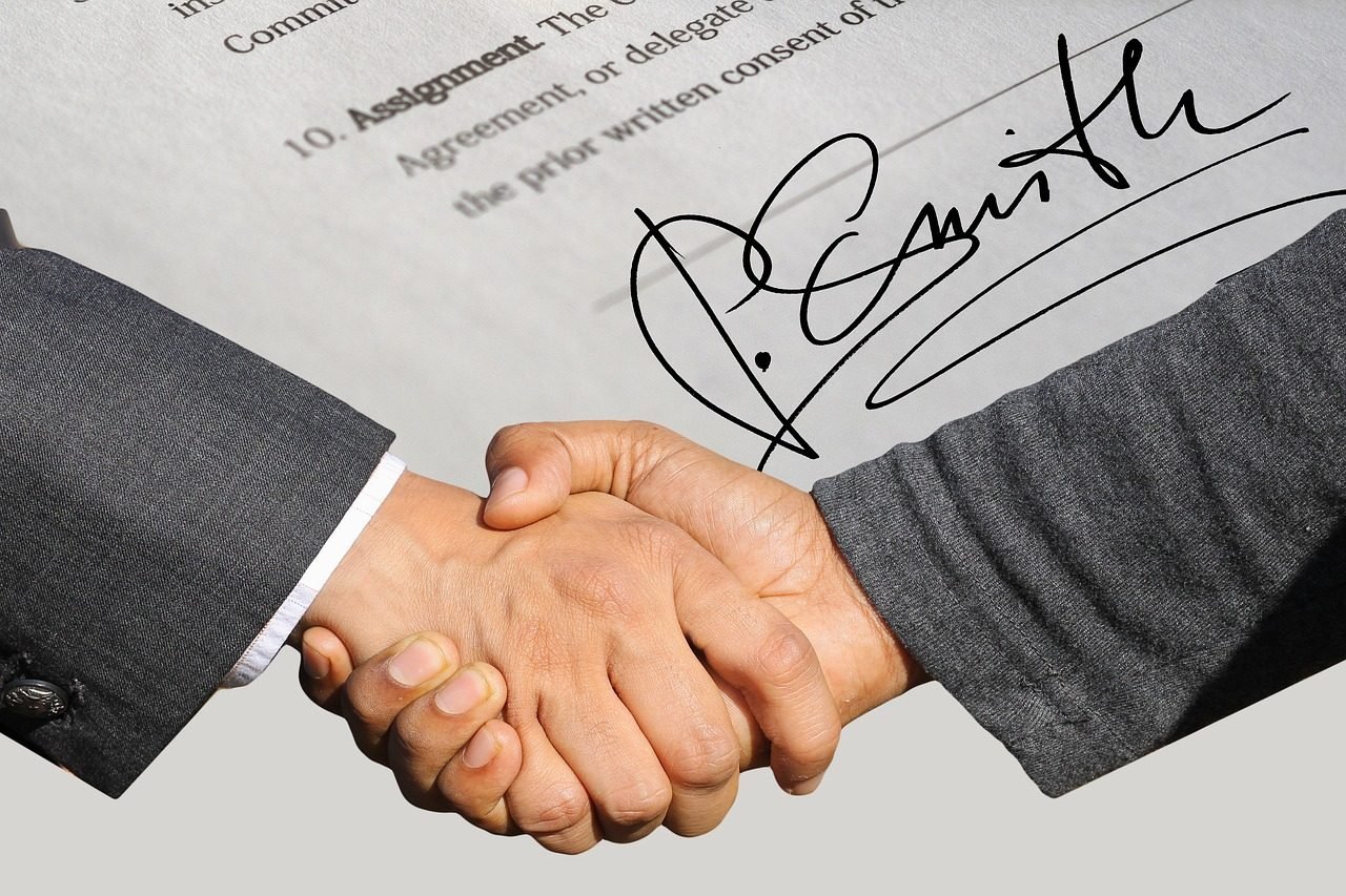 Aperto de mãos sobre um contrato assinado