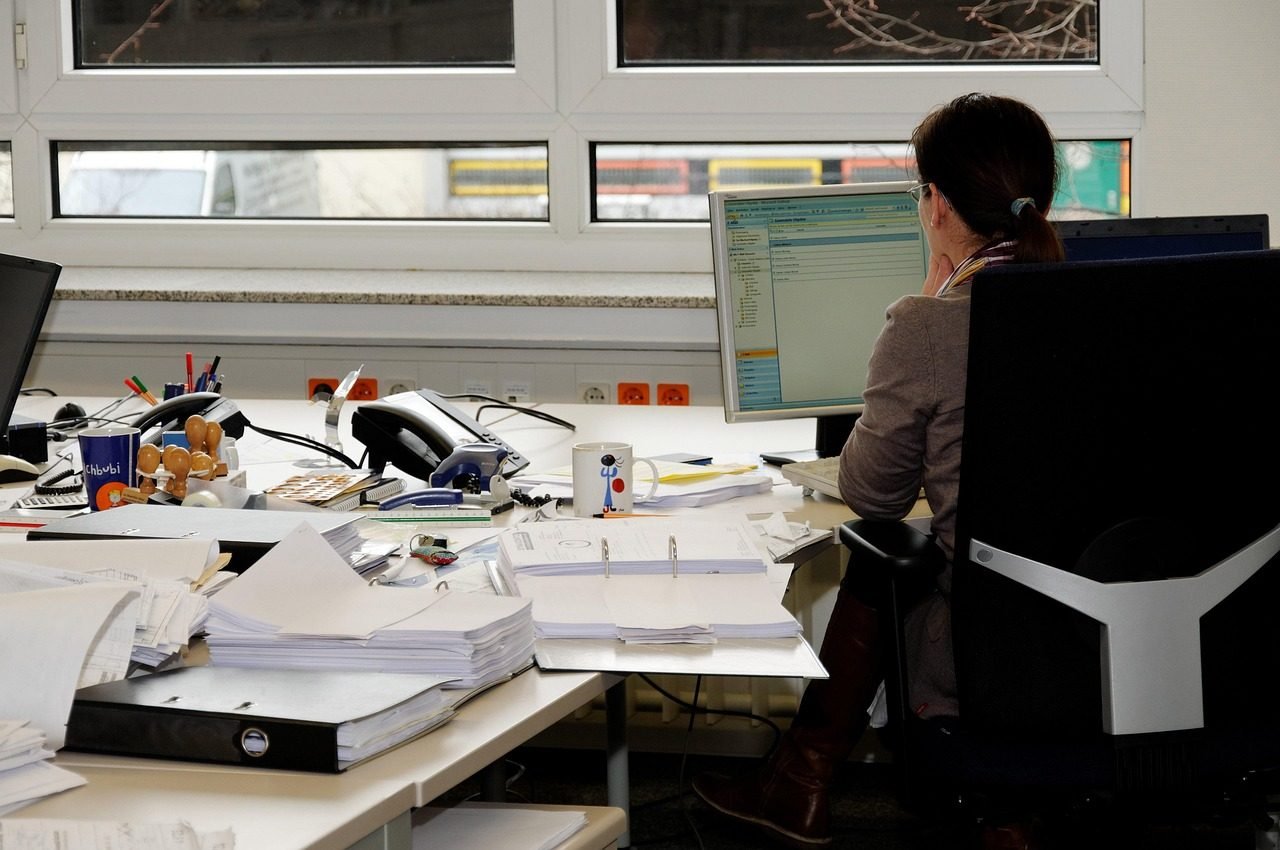 Pessoa ao telefone em mesa de escritório coberta de papéis
