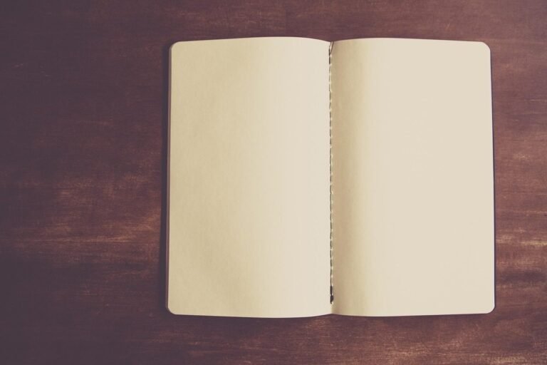 Caderno aberto em folhas em branco sobre superfície de madeira