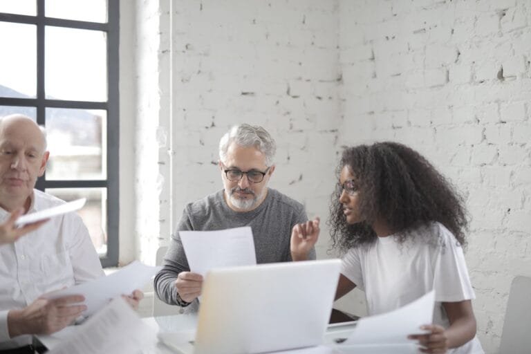 Pessoas idosas e consultora analisam documentos à mesa