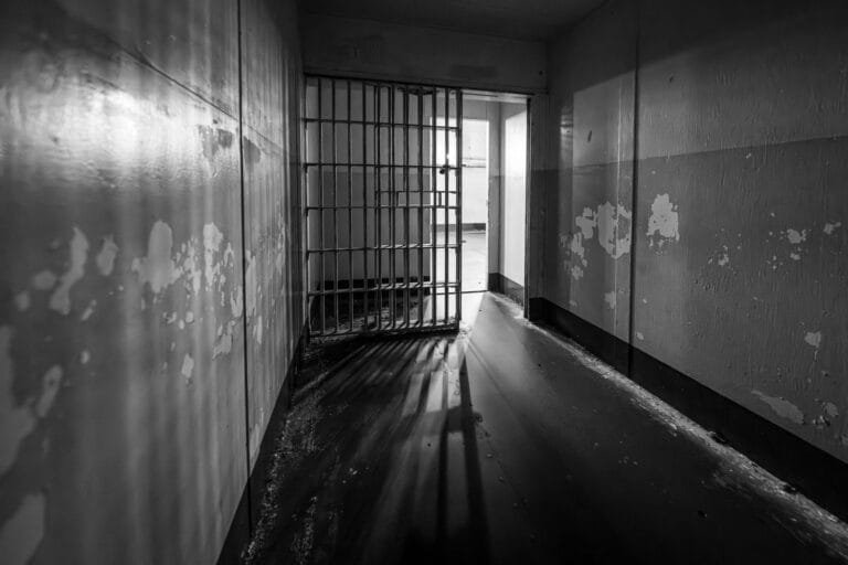 Saída temporária na execução penal: hipóteses legais e limites atuais 7 Porta gradeada de cela aberta, com luz entrando pelo corredor